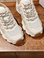 Two white lace-up sneakers side view, perforated panels and chunky rubber sole