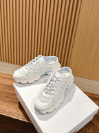 Pair of white Dior lace-up sneakers on display box, lace closure and textured sole