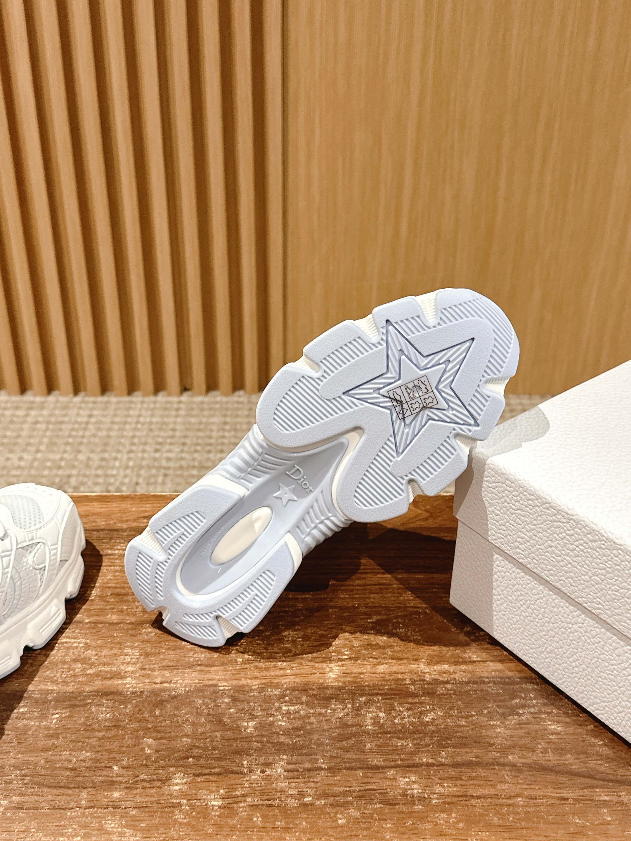 White Dior sneaker outsole view with star-shaped tread and textured grip