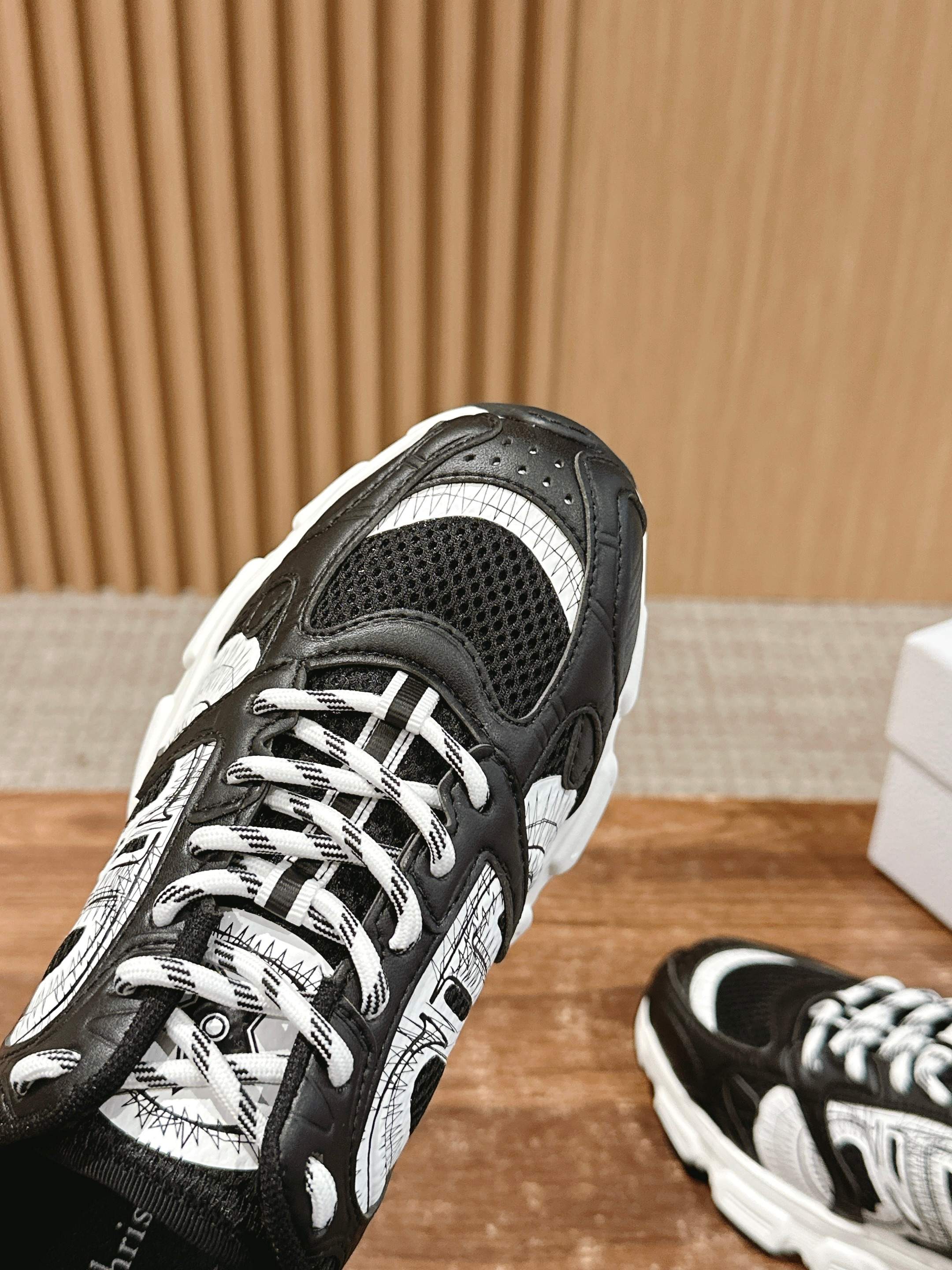 Dior lace-up sneaker close-up, black mesh and white panels with lace detail