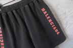Black Balenciaga shorts with elastic waistband and vertical red Balenciaga text