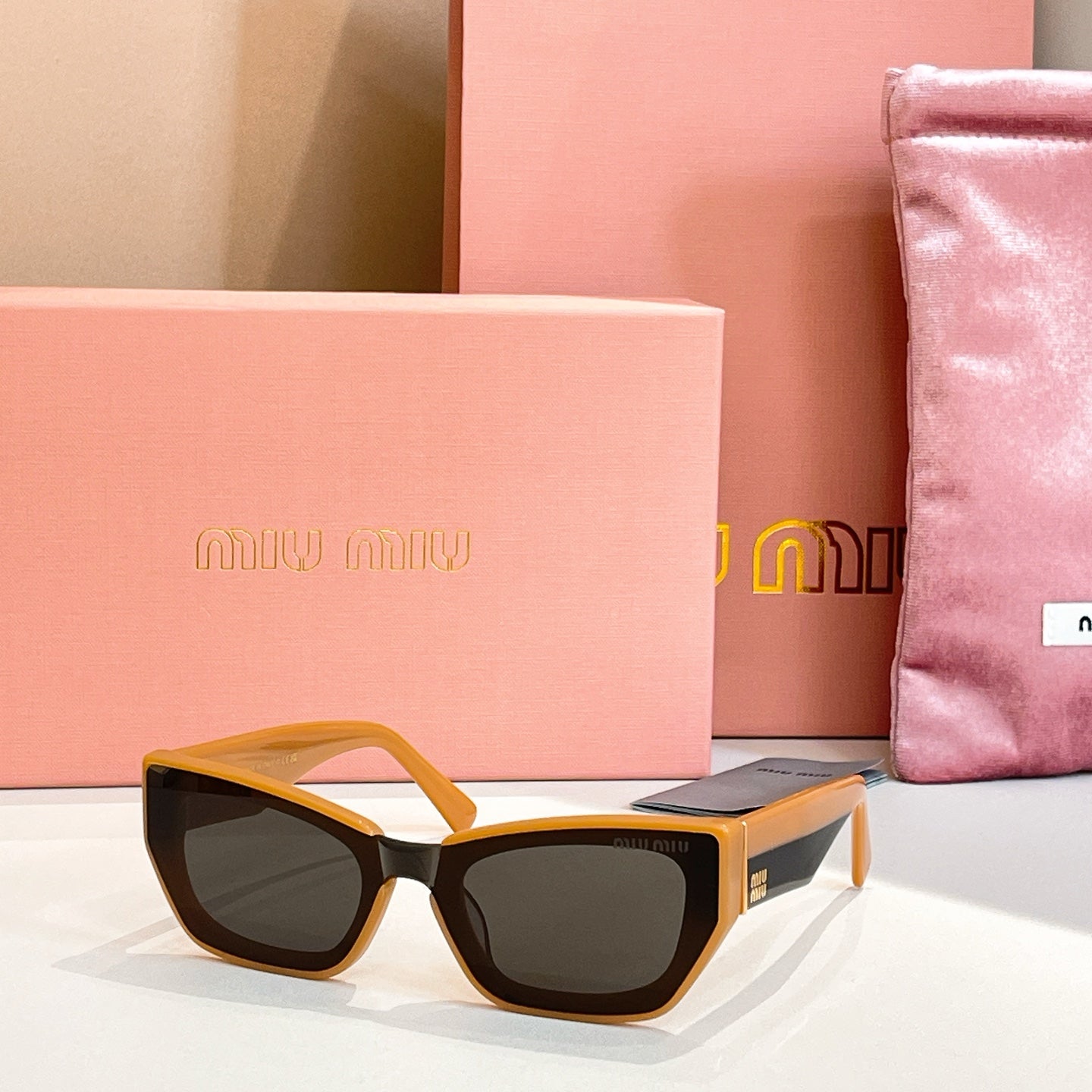 MiuMiu sunglasses with yellow frames and dark lenses.