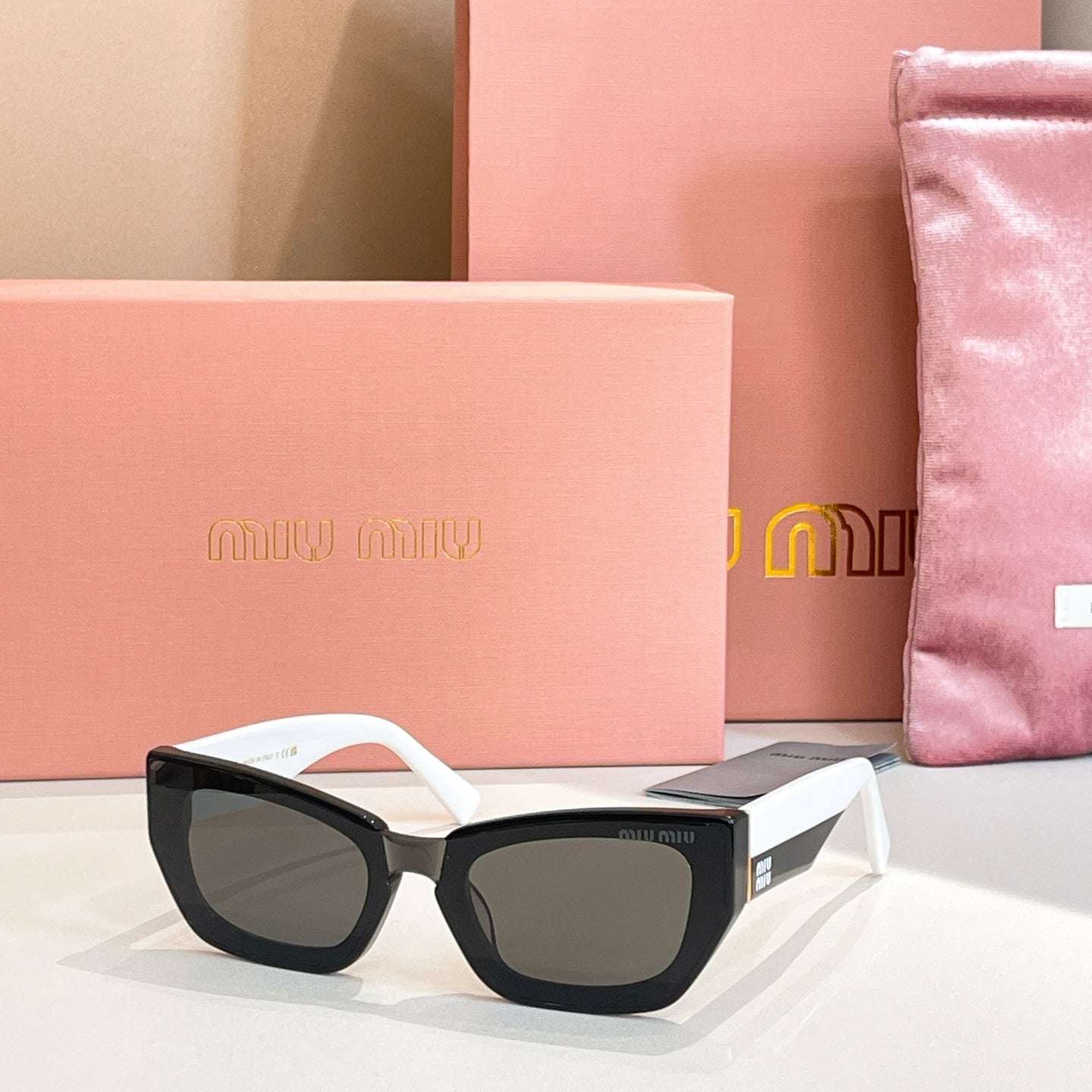 MiuMiu sunglasses with black frames and white arms, dark lenses.