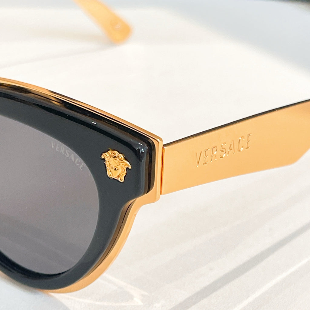 Versace sunglasses close-up, gold temple arm and dark lens with cat-eye frame
