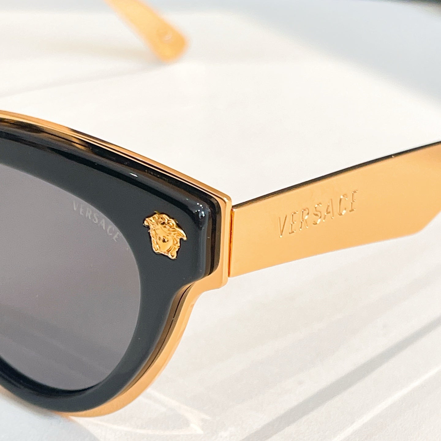 Versace sunglasses close-up, gold temple arm and dark lens with cat-eye frame