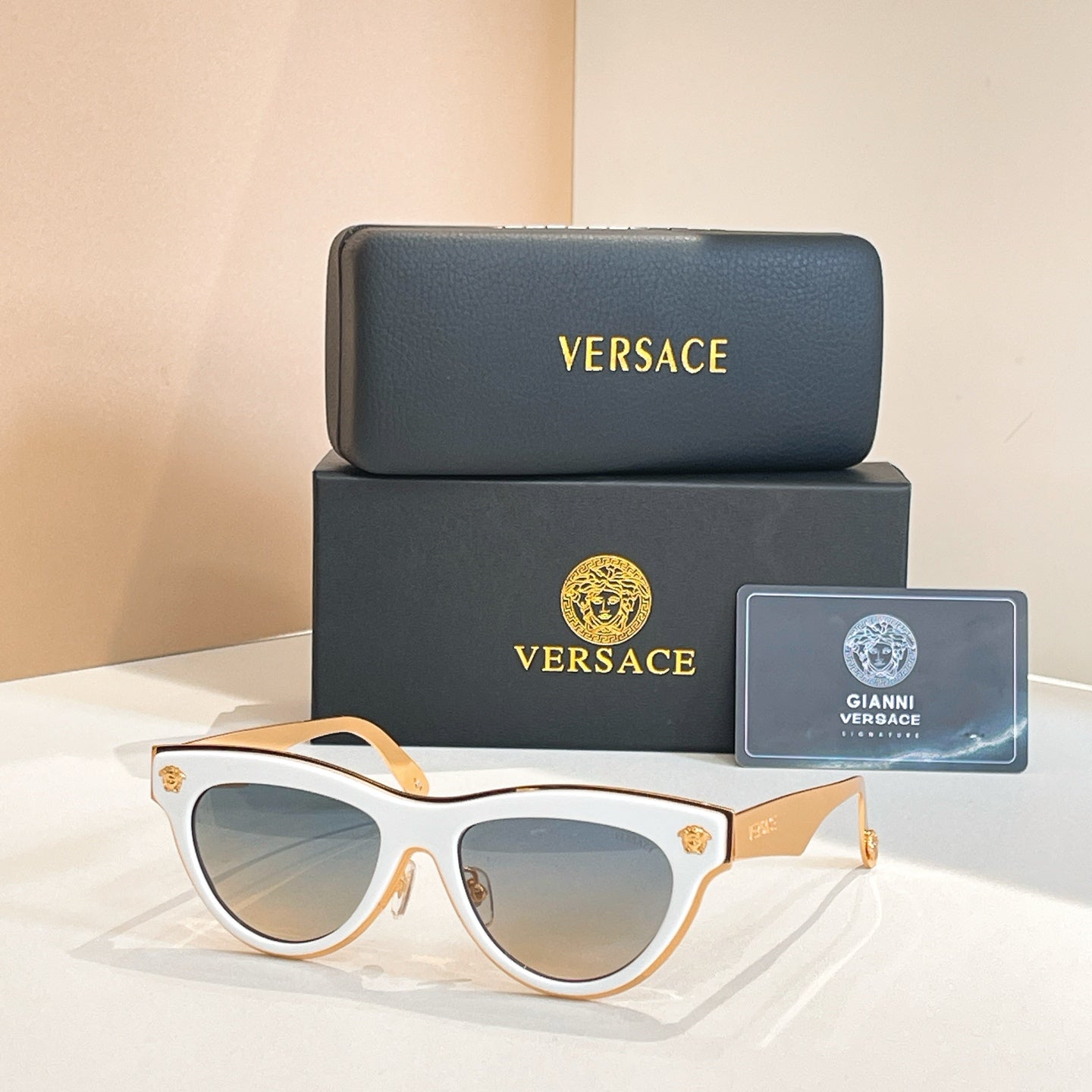 Versace sunglasses, white cat-eye frames with dark tinted lenses and gold logo temples