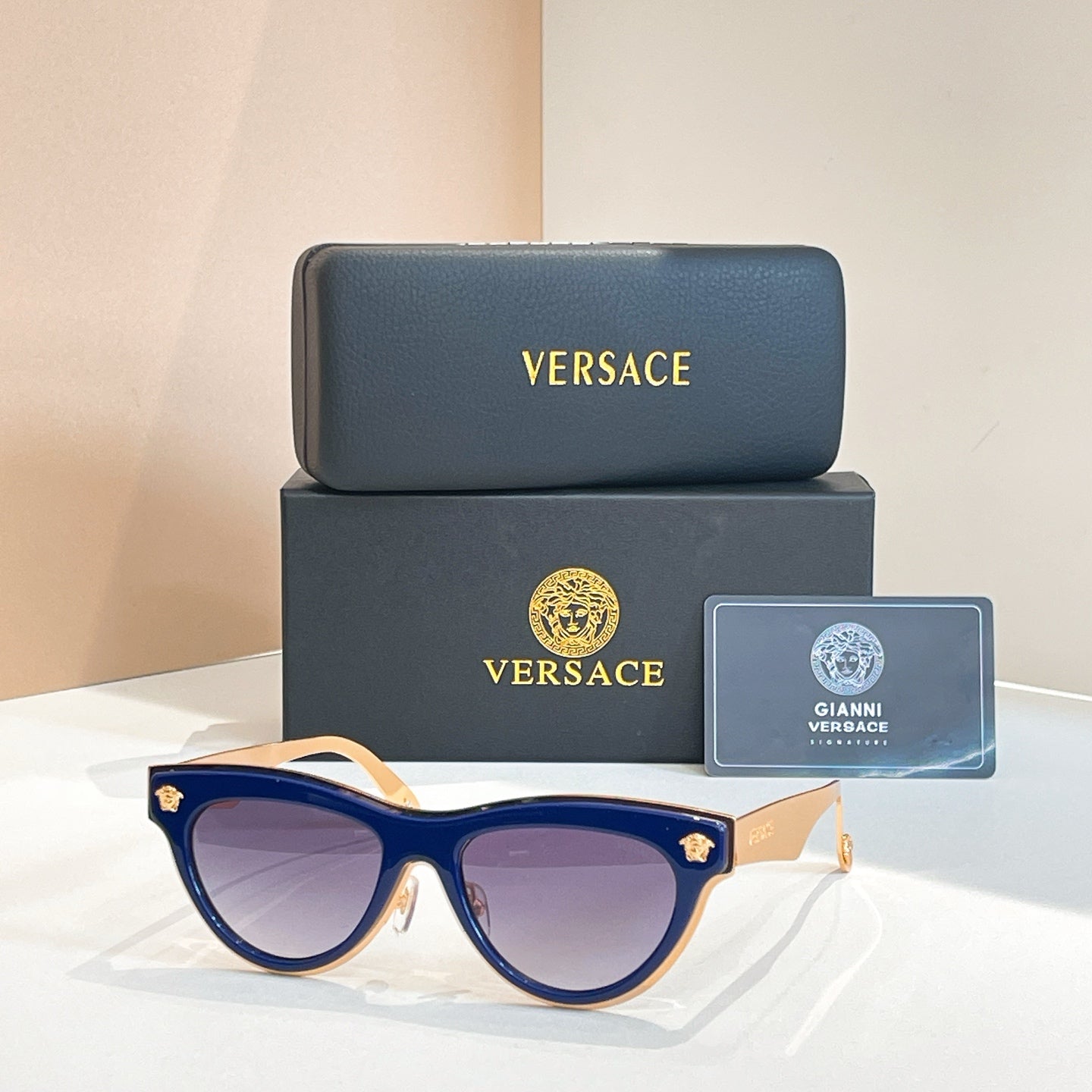Versace sunglasses, navy cat-eye frames with dark tinted lenses and gold logo temples