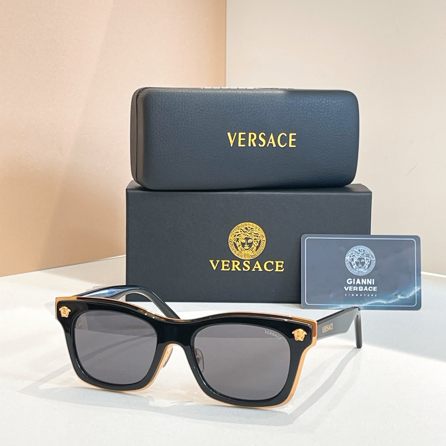 Versace sunglasses with black frames, rounded lenses, and gold emblem temple tips
