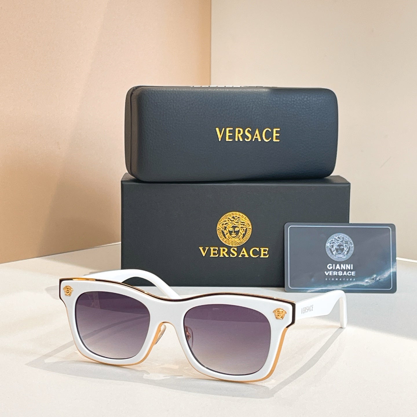 Versace sunglasses with white frames, purple-tinted lenses, and gold emblem temple tips