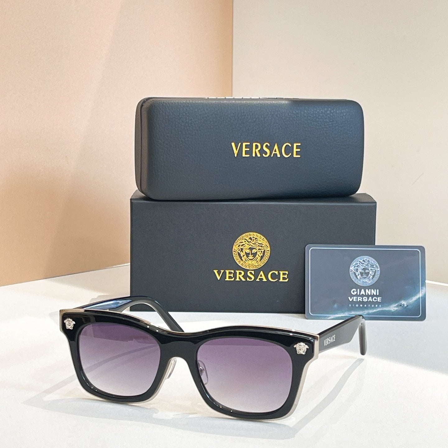 Versace sunglasses with black frames, round-square lenses, and gold emblem temple tips