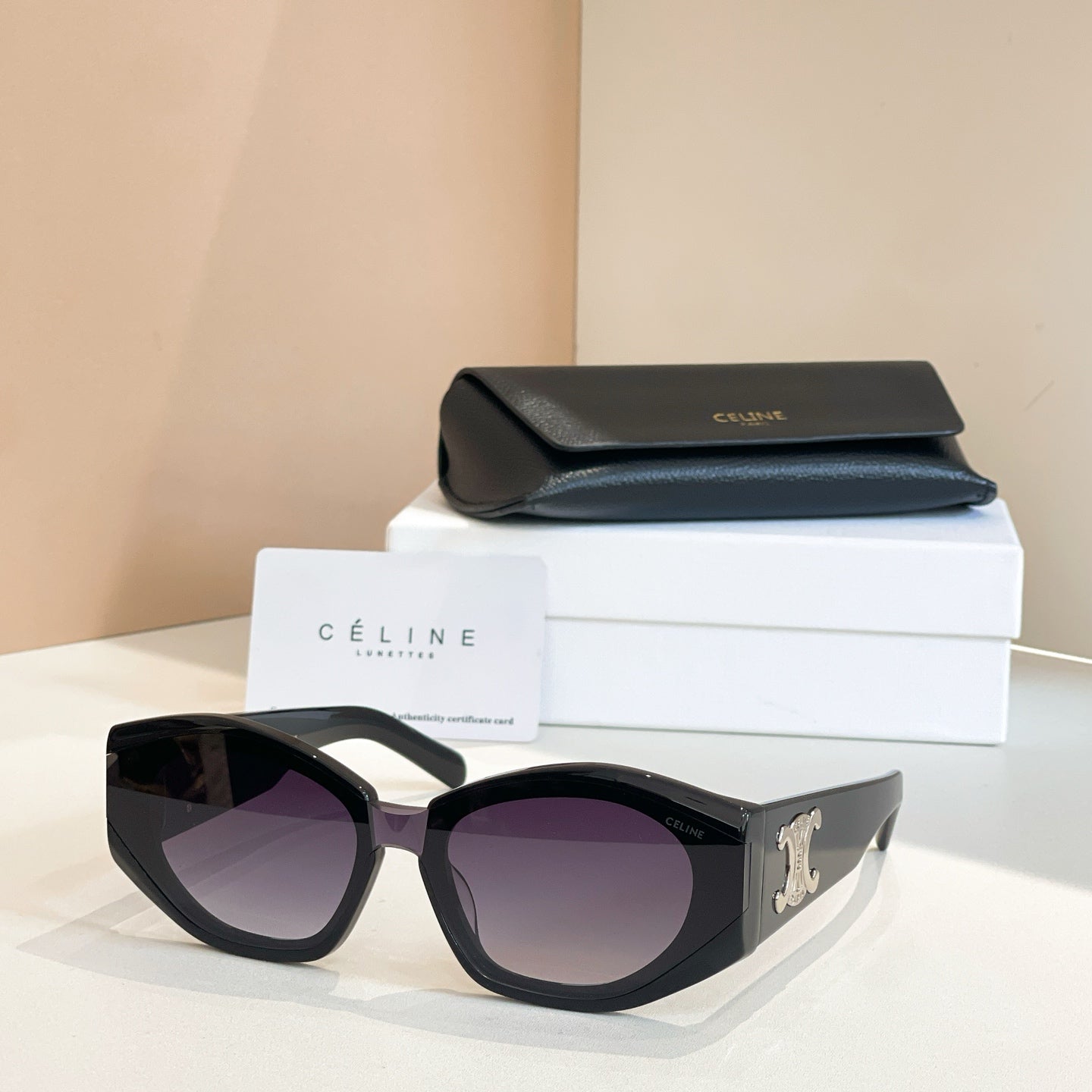 Black cat-eye sunglasses with gold logo detail and purple-tinted lenses.