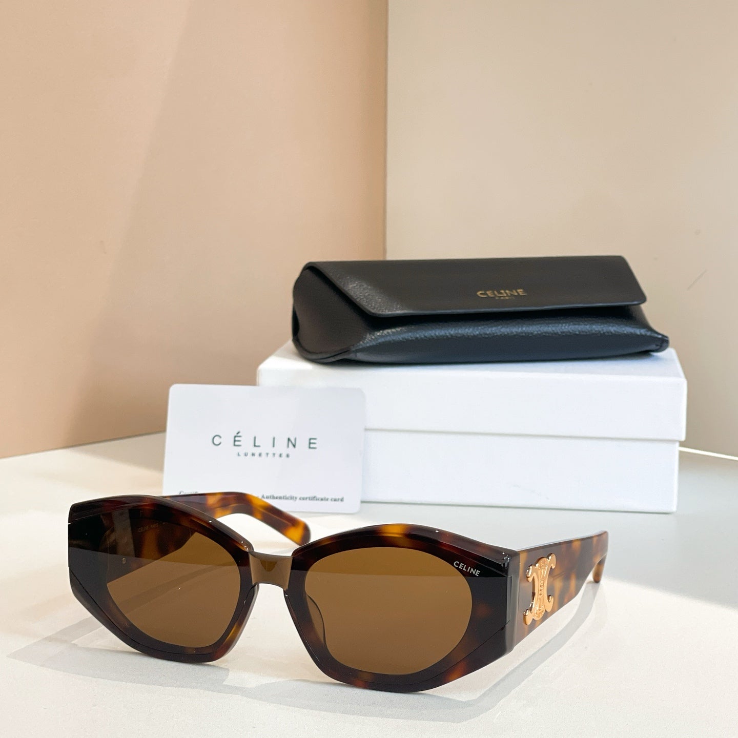 Tortoiseshell cat-eye sunglasses with gold logo detail and amber lenses.