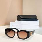 Black cat-eye sunglasses with gold logo detail and amber-tinted lenses.