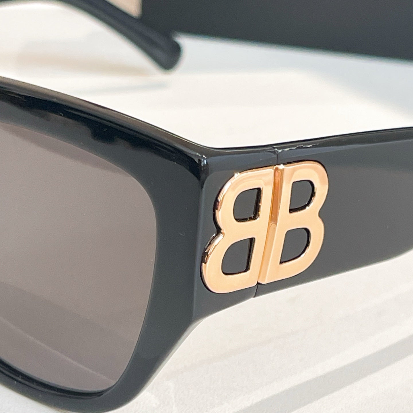 Black sunglasses with gold-tone "B" logo on the temple