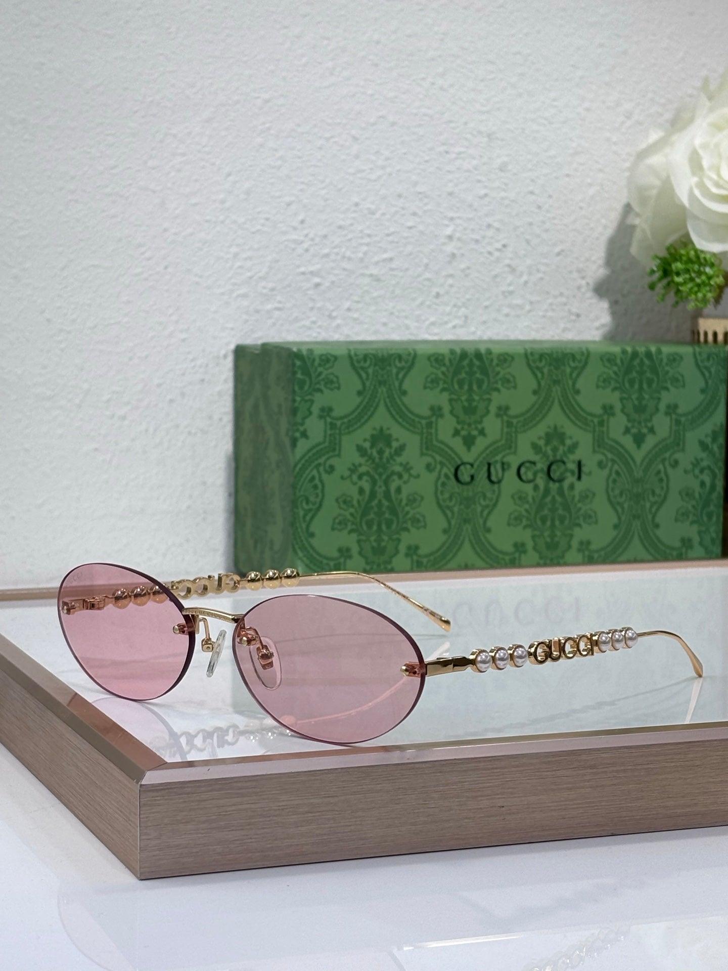 Gold-tone round sunglasses with pink lenses and decorative chain detail on temples
