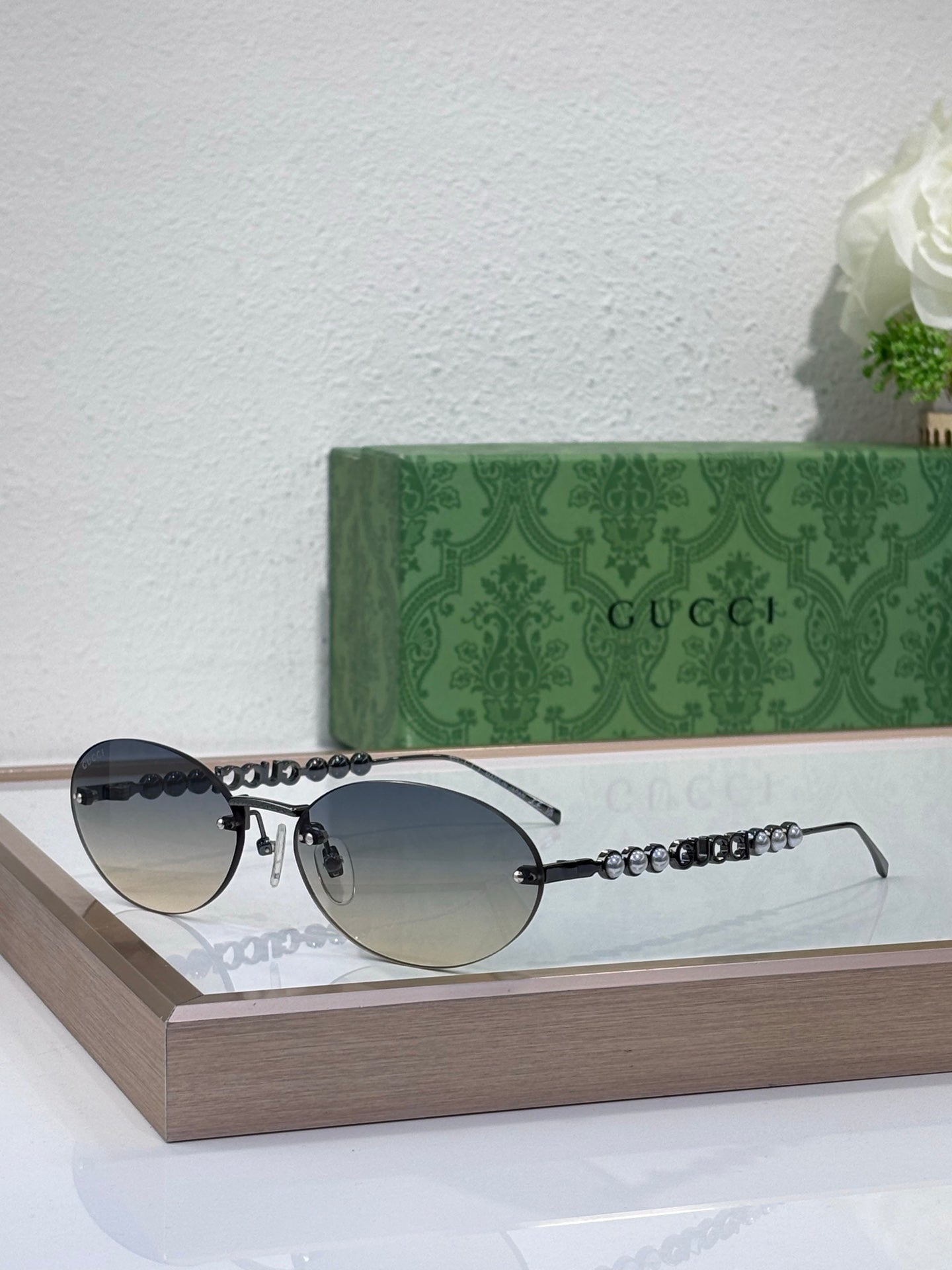 Round sunglasses with dark lenses, gold-tone frame, and beaded chain temple detail