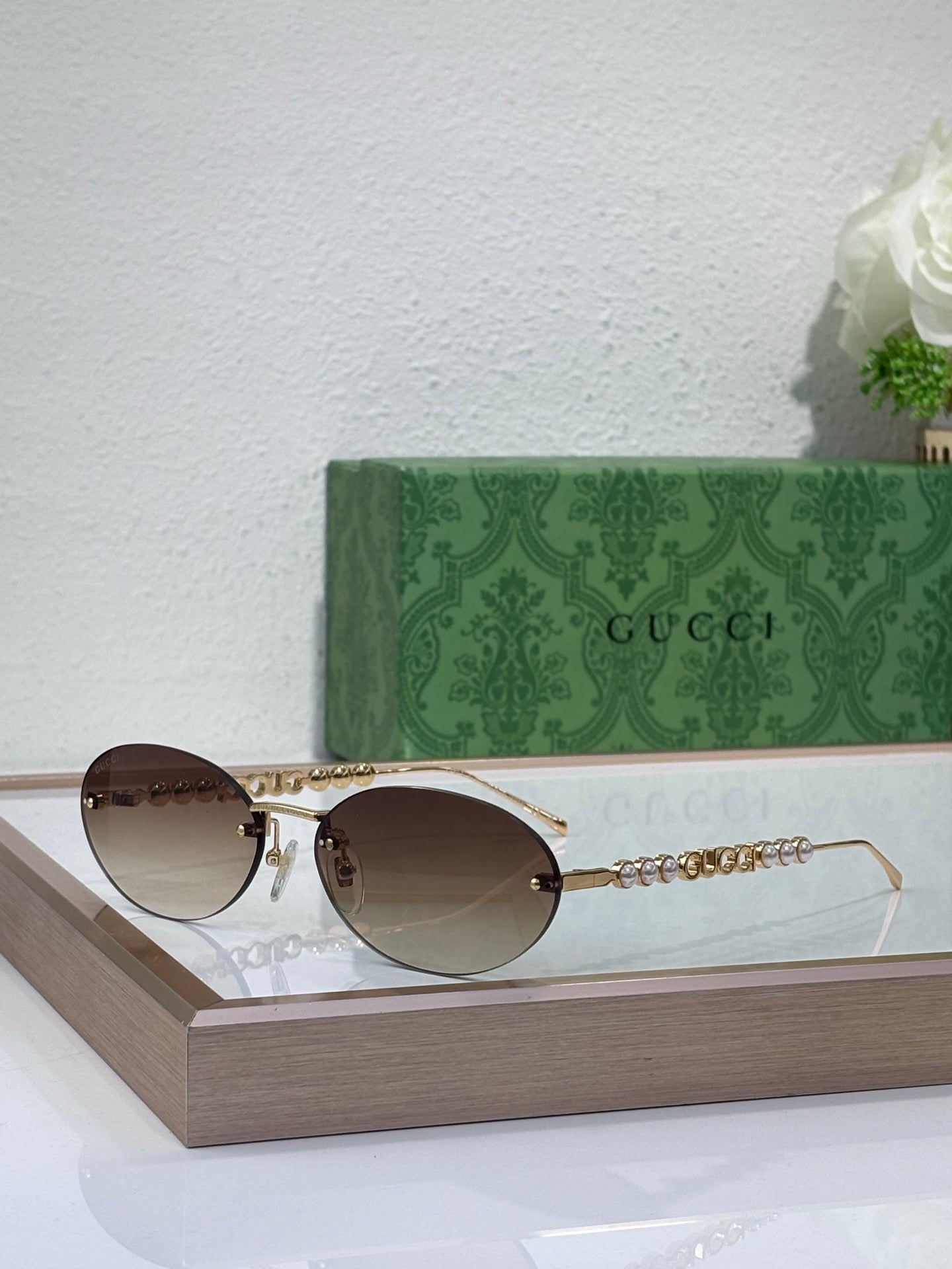 Gold-tone round sunglasses with dark lenses, curved bridge, and chain temple accents