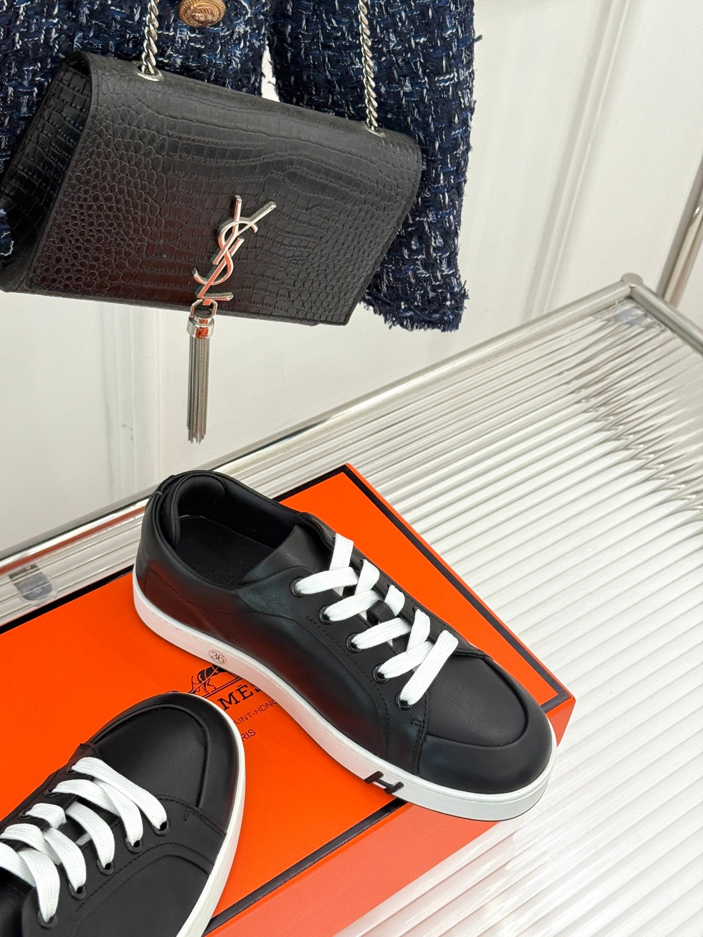 Black lace-up sneakers with white laces and low white rubber sole, cropped side view.
