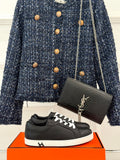 Black leather-look sneakers with white laces and low white rubber sole, lace-up.