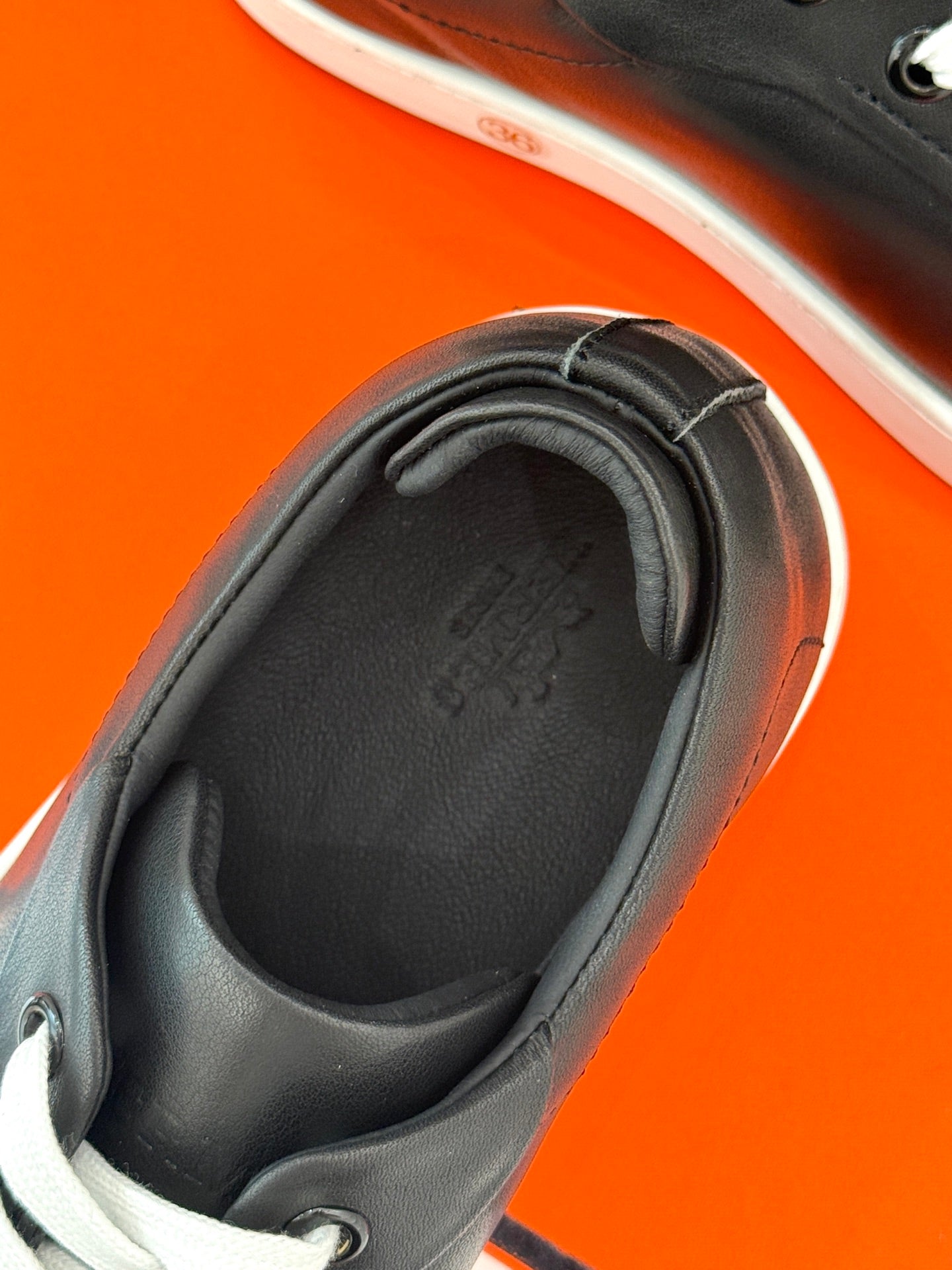 Black sneaker interior and collar detail with low white rubber sole trim, close-up.