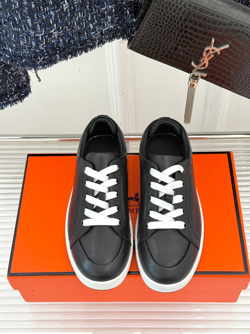 Black leather-look sneakers with white lace-up detailing and low white rubber sole, front.