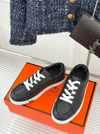 Black lace-up sneakers with white laces and low white rubber sole, angled top view.