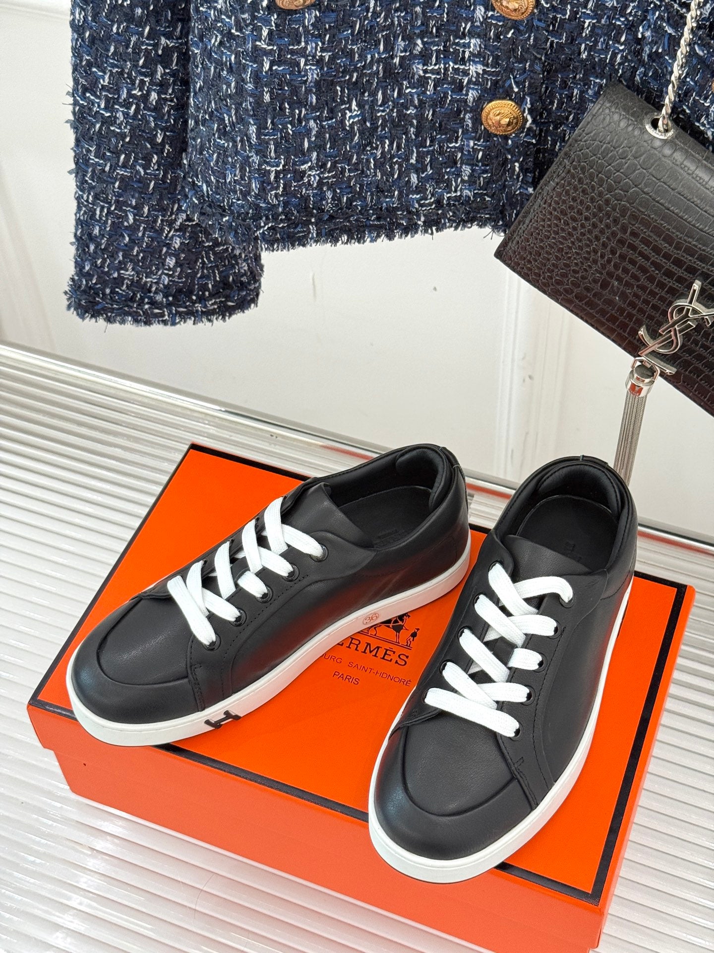 Black lace-up sneakers with white laces and low white rubber sole, angled top view.
