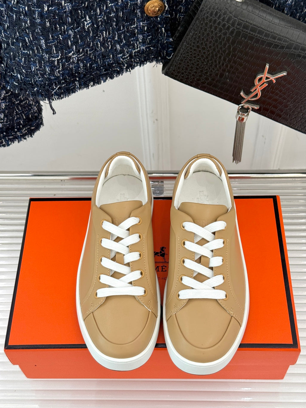 Front view of ladies' Hermes sneakers, tan leather with white laces and white sole