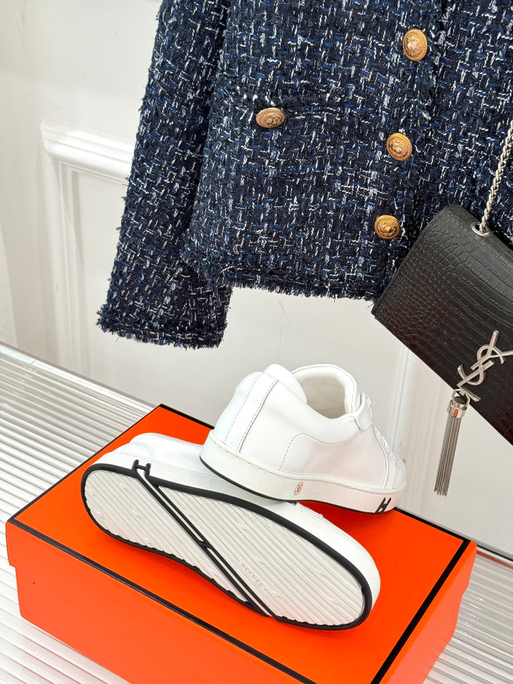 White leather sneakers with heel and textured outsole on an orange shoebox.