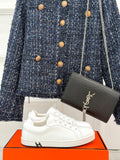 White leather low-top sneakers with lace-up front and rubber sole.