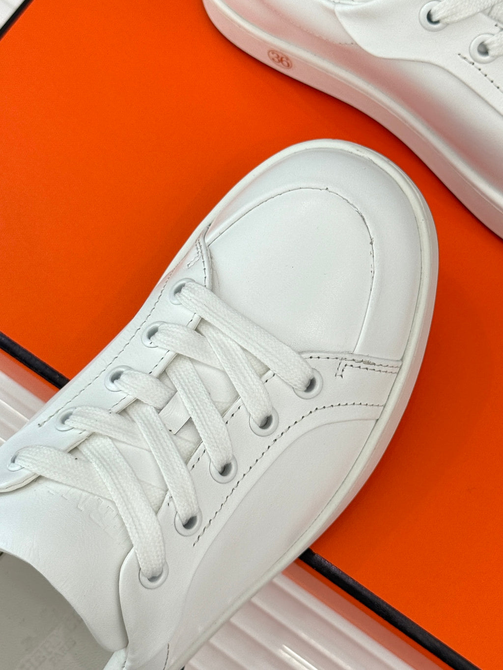 White leather sneaker with lace-up vamp and smooth toe cap.