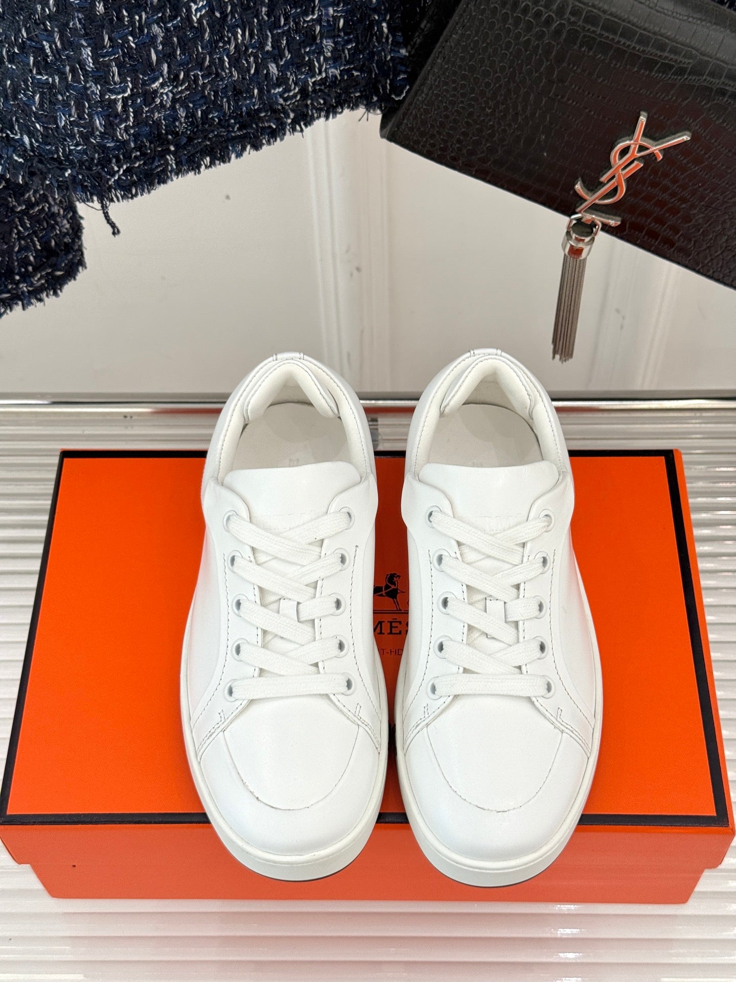 White leather low-top sneakers with lace-up closure, front view.