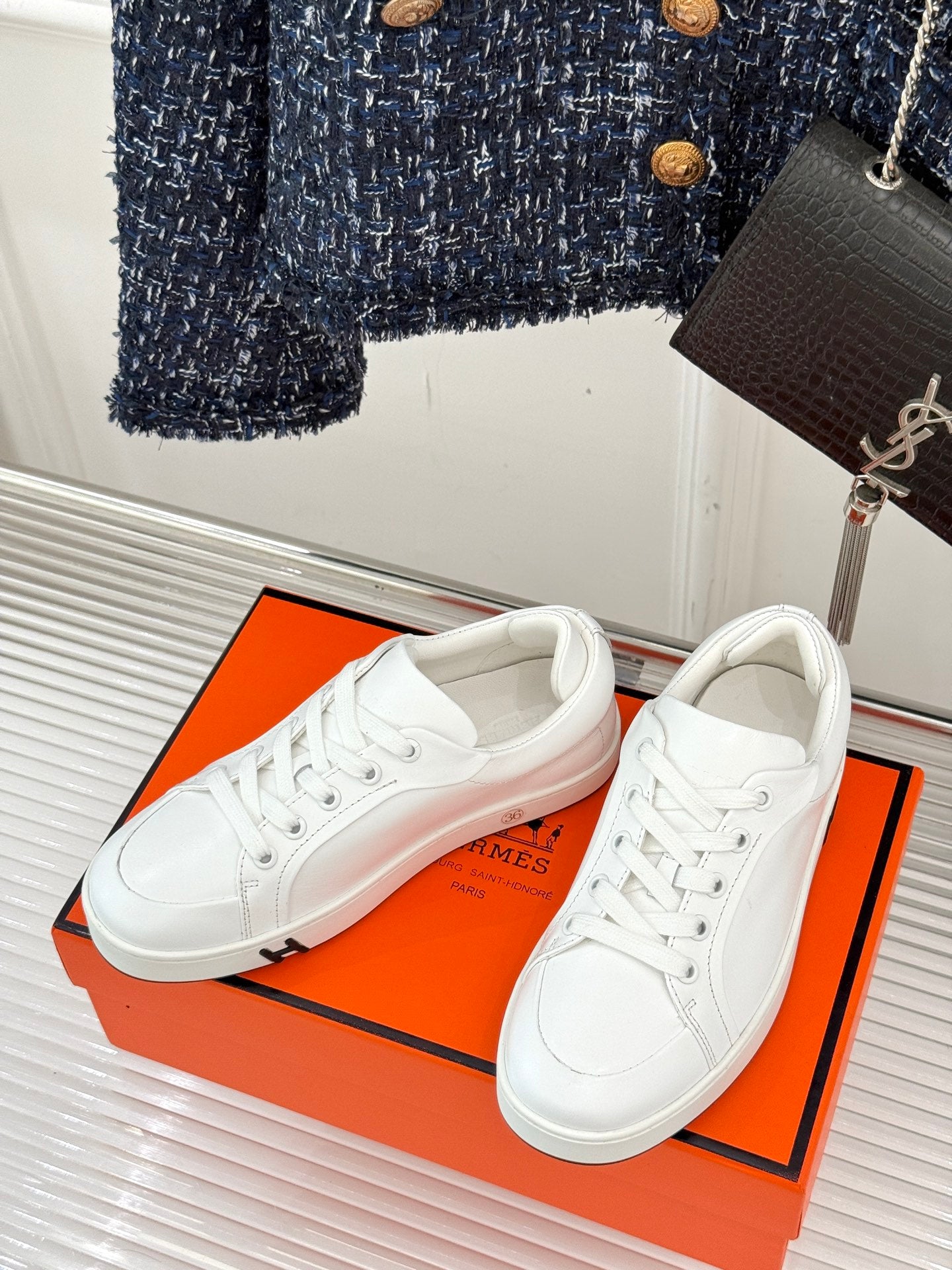 White leather lace-up sneakers, paired shoes on an orange shoebox.