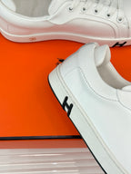 White leather sneaker toe with laces and pink sole trim detail.