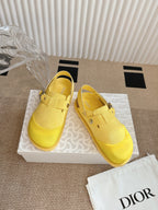 Yellow unisex shoes on patterned box, side view, buckle strap details
