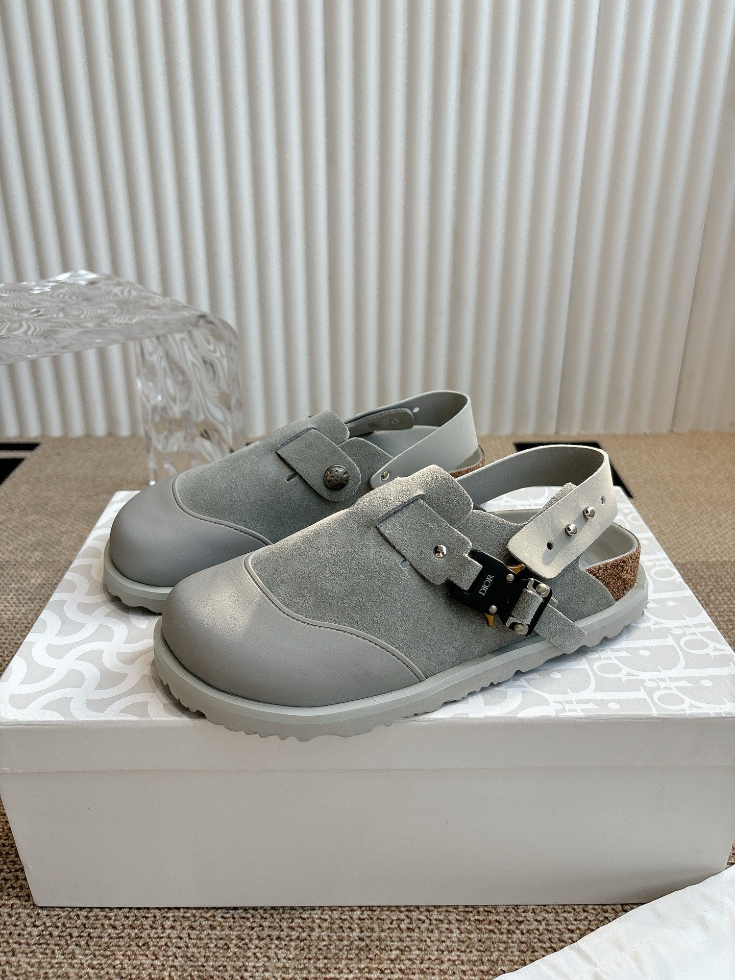 Light gray slip-on shoes with double straps and metal buckle detail