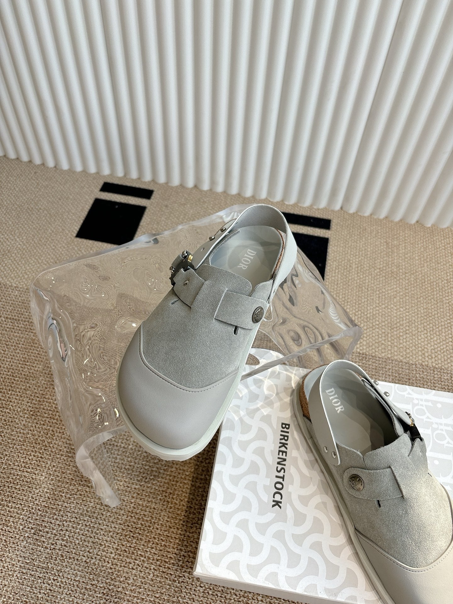 Light gray slip-on shoes with buckle strap on top and side view