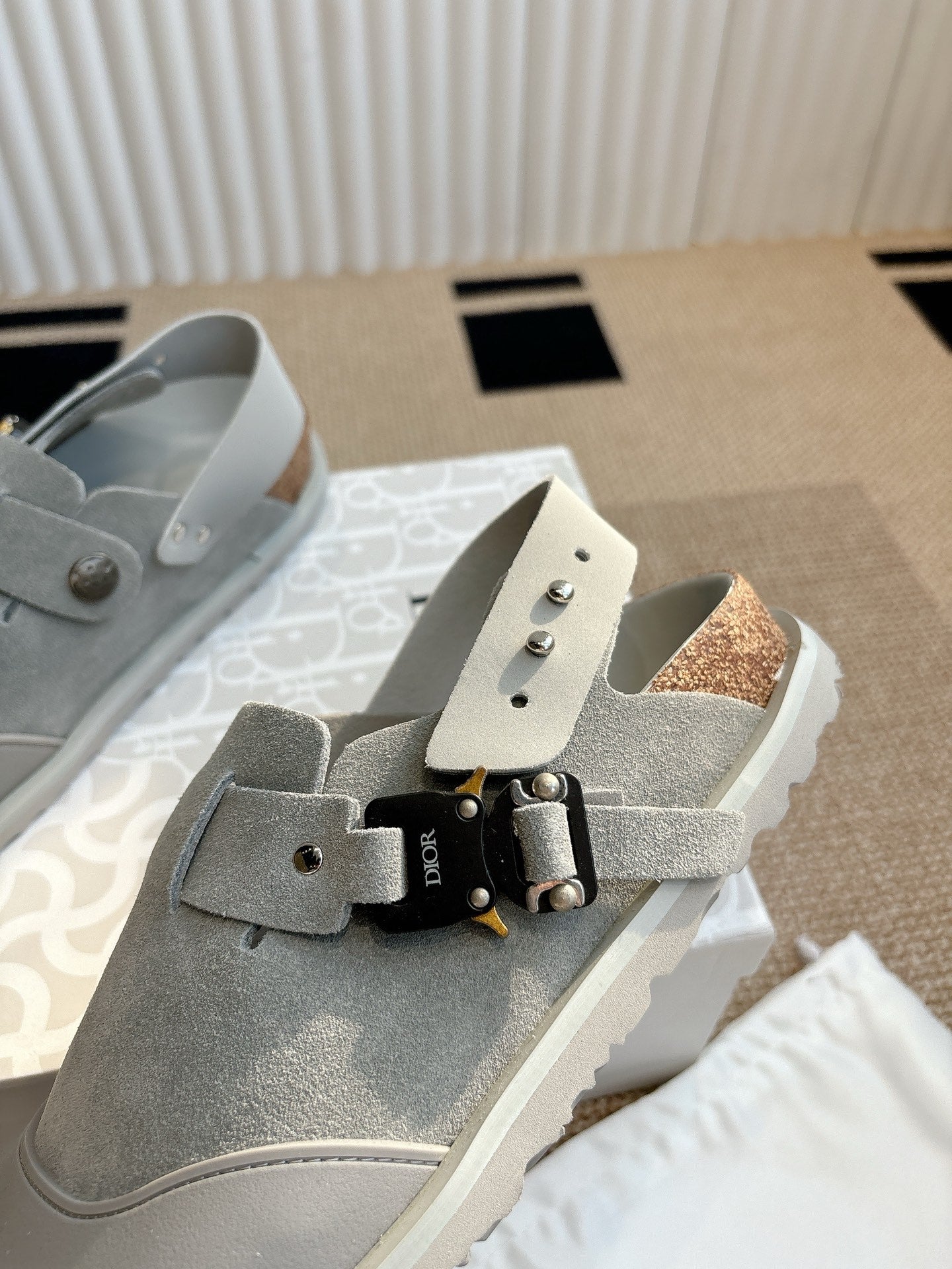 Light gray slip-on shoe with front strap buckle and textured side panel