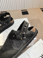 Black and dark gray sandals with felt straps, metal eyelets, and buckle closures