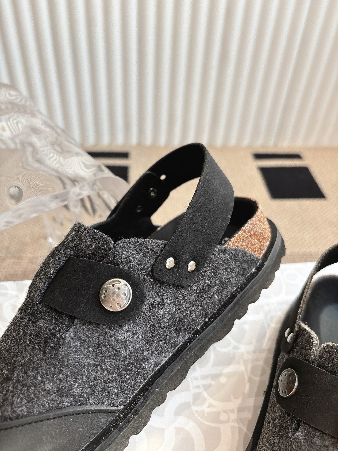 Black and dark gray slip-on sandal with felt upper and round decorative buckle