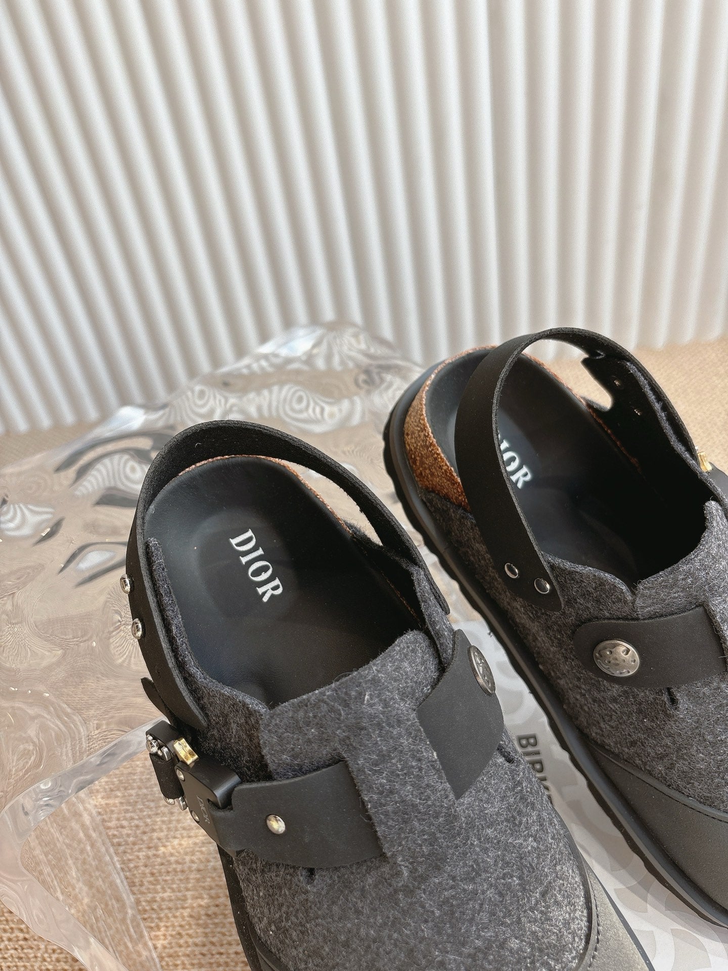 Black and dark gray slip-on shoes with felt uppers and buckle detail on sides