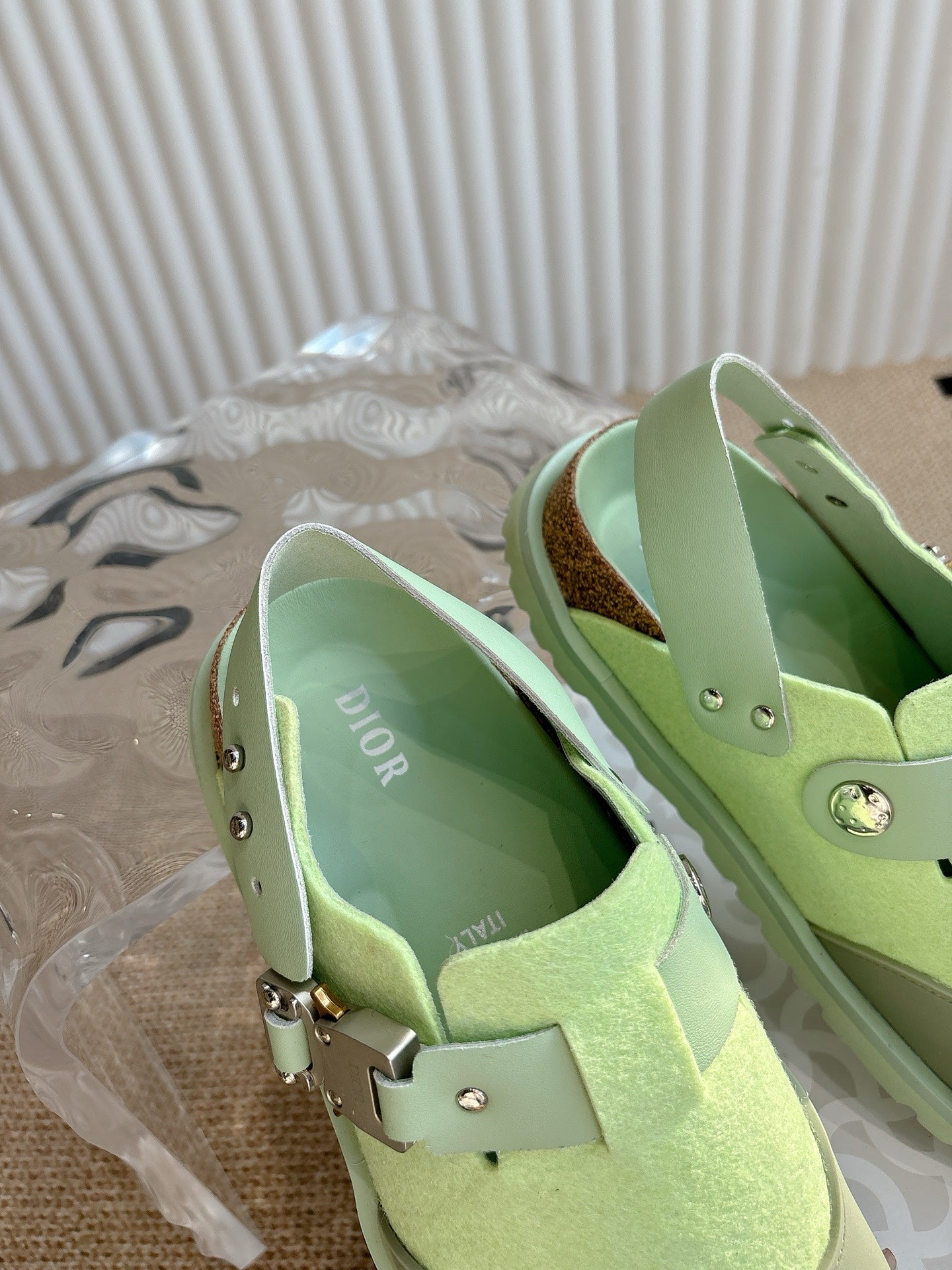 Unisex green sneakers with interior lining and metal strap hardware, close-up