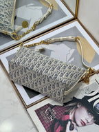 Crossbody bag with blue-and-white monogram print, gold chain strap, and white top handle.