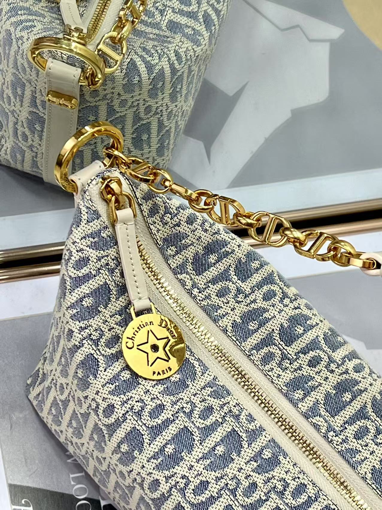Dior monogram bag detail with gold zipper pull and star charm, blue and white
