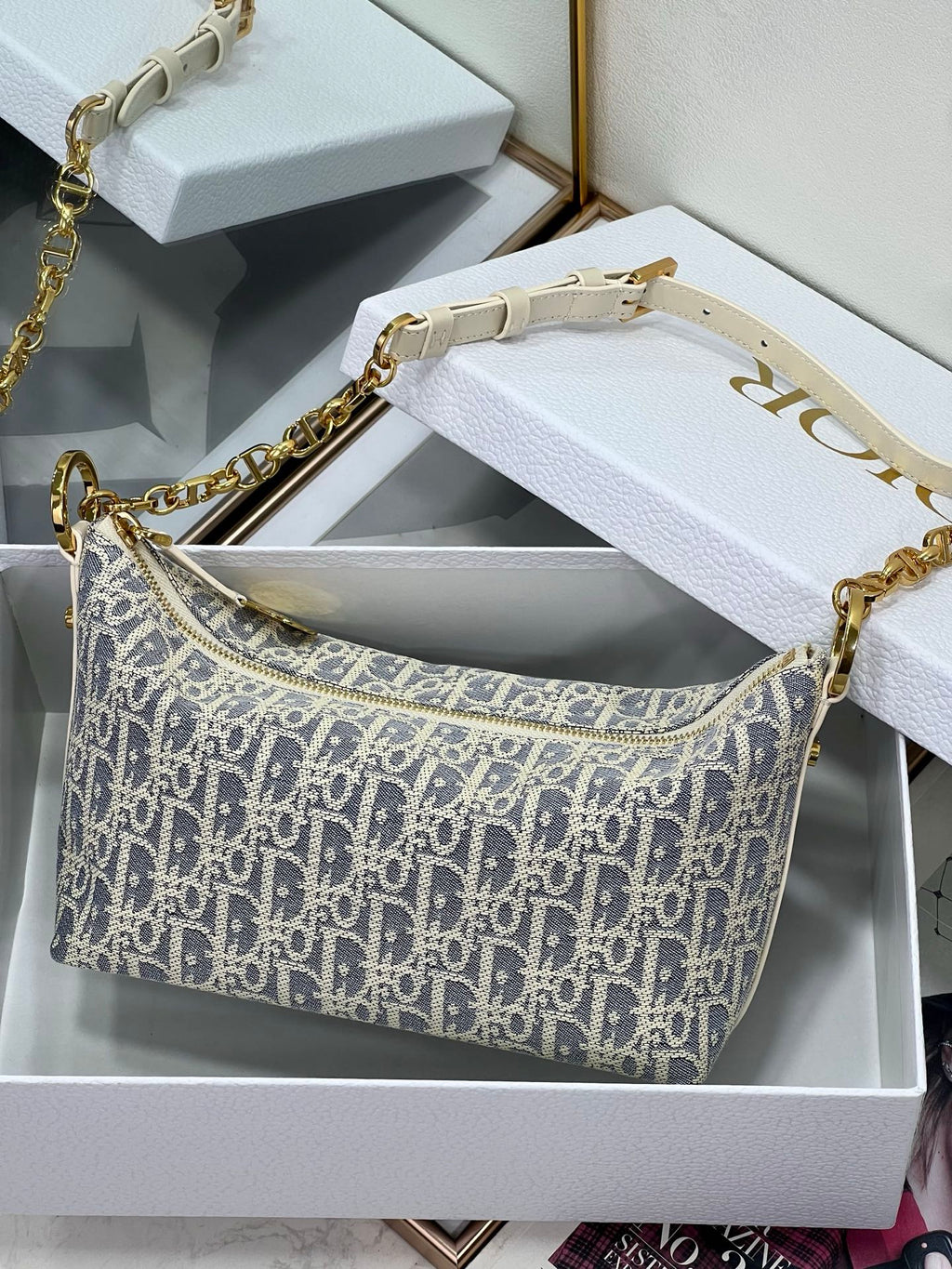 Mini crossbody bag with blue-and-white monogram print, gold chain strap and white leather trim.