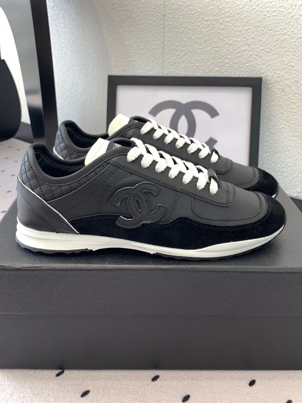 Black Chanel low-top sneakers, side view with white laces and CC emblem