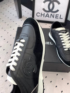 Black Chanel sneakers side view with white laces, CC logo on the quarter
