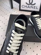 Black Chanel sneakers close-up of laces and CC logo on the tongue