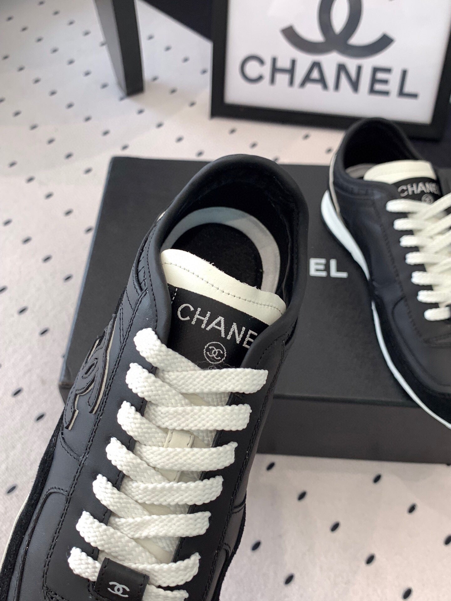 Black Chanel sneakers close-up of laces and CC logo on the tongue