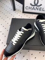Black Chanel sneakers held up, front-left view with white laces and white sole